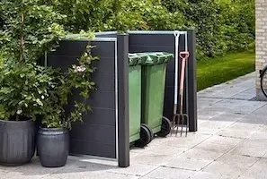 Einen Sichtschutz für Mülltonnen aufstellen – so geht‘s Moderne Mülltonnenverkleidung aus WPC mit Metallpfosten, sorgt für eine stilvolle und ordentliche Müllplatzgestaltung im Garten.