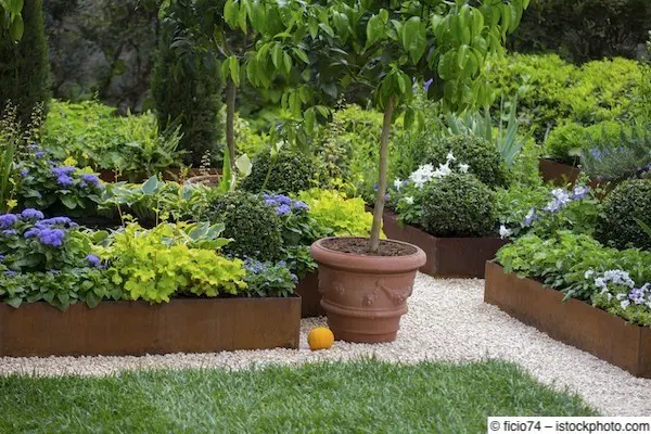 Mehrere rötlich-braun gefärbte Beeteinfassungen aus Cortenstahl, durch Kieswege getrennt