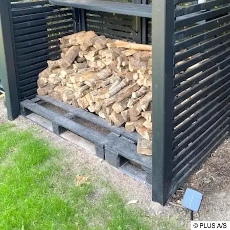 Niedriger Brennholzstapel in Holzunterstand