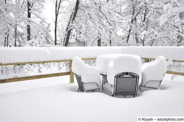 Tief verschneite Terrasse mit Gartenmöbeln aus Metall