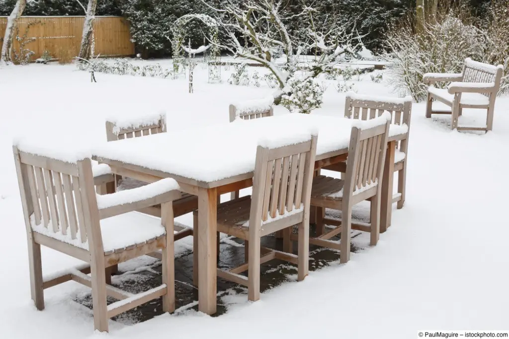 Schneebedeckte Sitzgruppe aus Gartenmöbeln auf winterlicher Terrasse