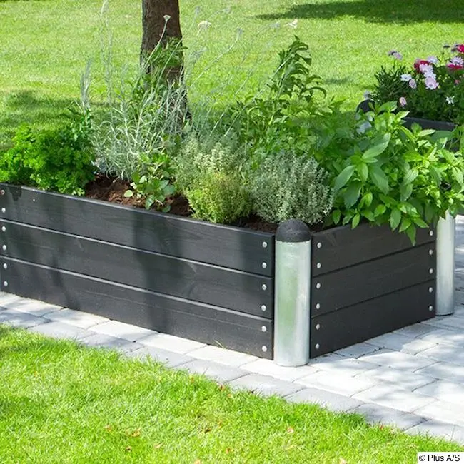 Hochbeet auf gefliester Terrasse, dahinter Rasen