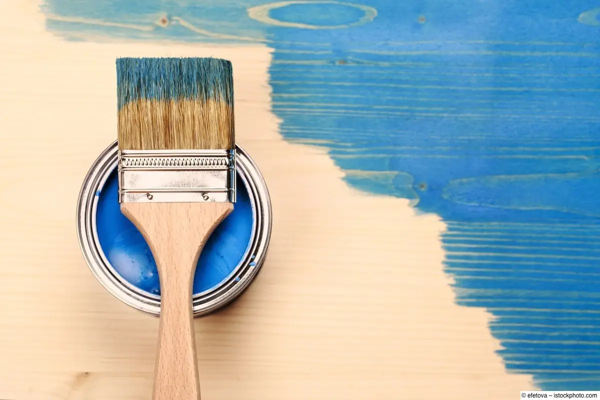 Dose mit blauer Holzfarbe, Pinsel und halb gestrichener Tischplatte